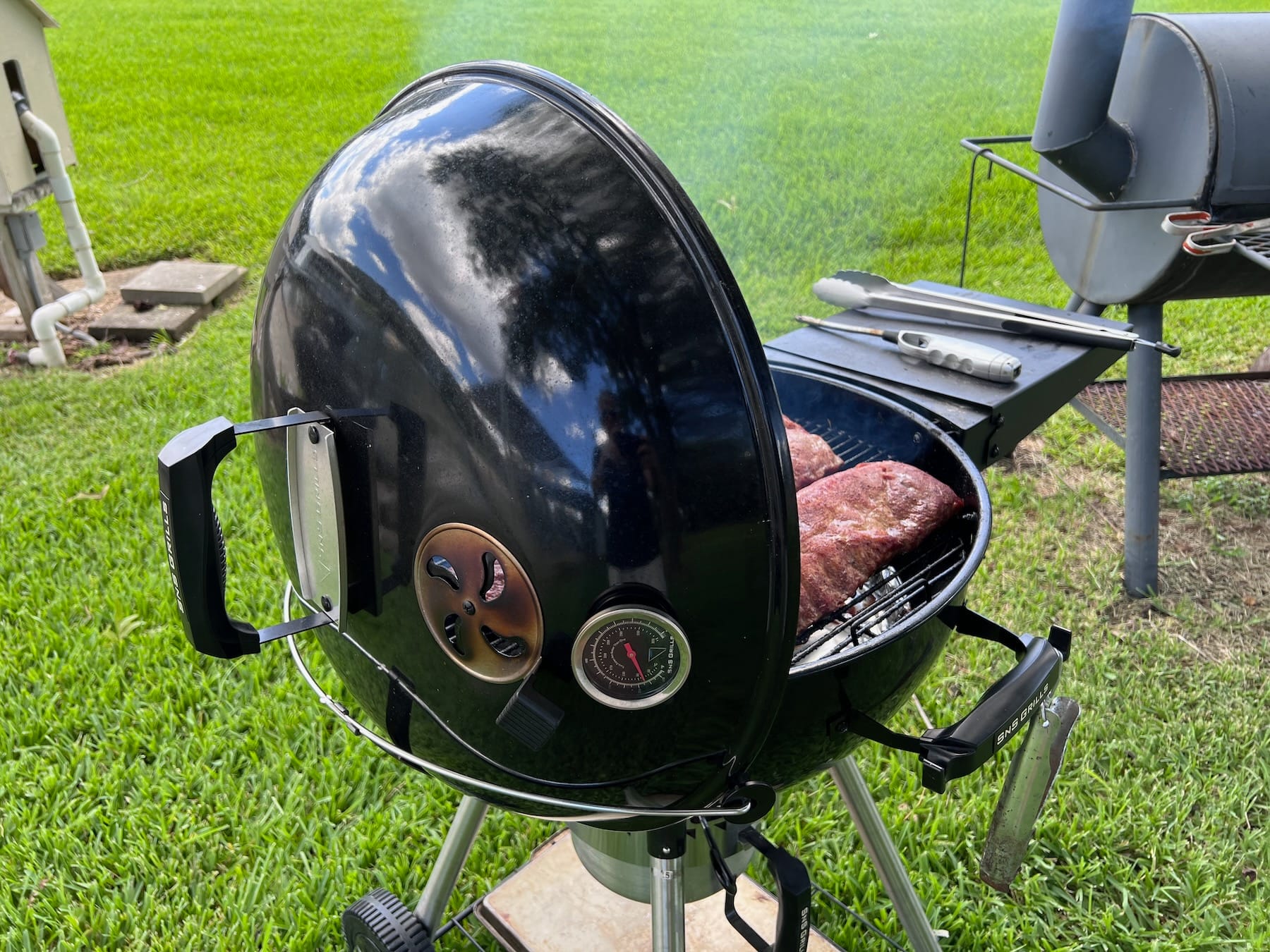 Lid sitting in cradle on Slow N Sear Kettle Grill.