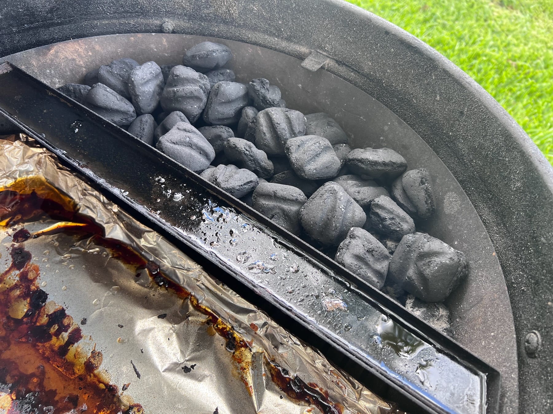 Water reservoir next to charcoal basket on Slow N Sear Deluxe insert that is included with the kettle grill.